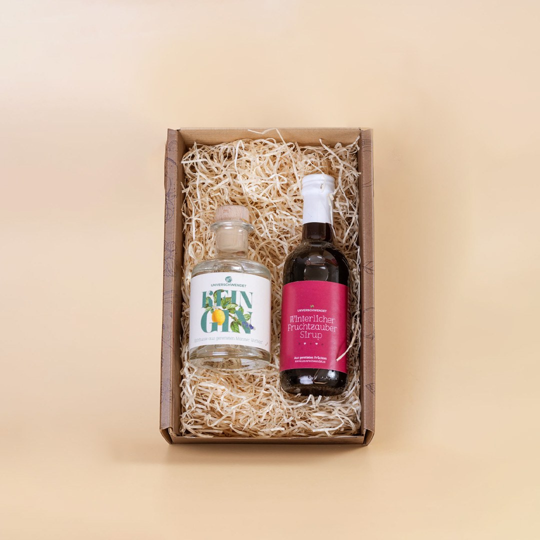 Geschenkbox mit Fruchtsirup und Kein-Gin-Flasche (vor apricot farbigem Hintergrund) Geschenkbox mit Fruchtsirup und Kein-Gin-Flasche